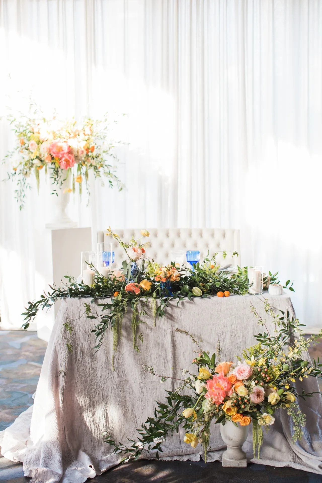 The sweetheart table, dressed with citrus, greenery, and blue glassware.